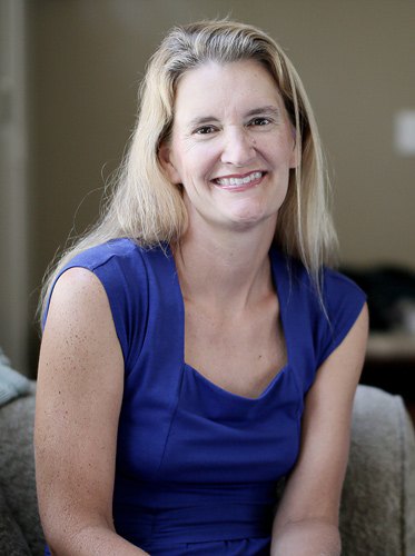 Jean Twenge smiling, in a blue sleeveless top, seated in front of a soft background