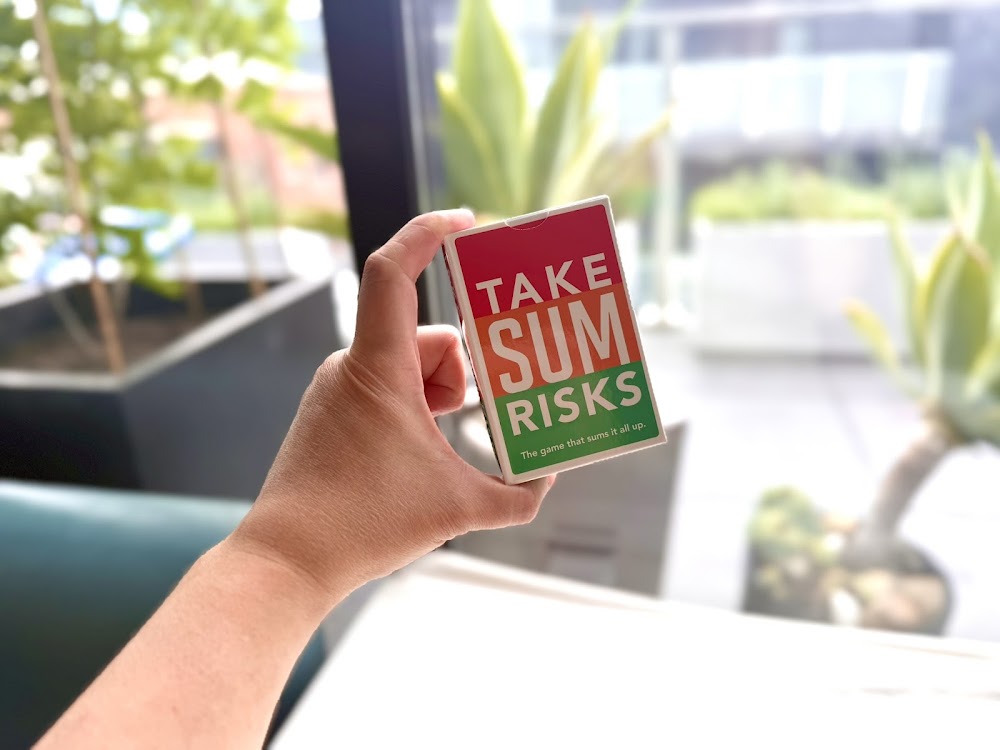 A hand holding the small Take Sum Risks card box