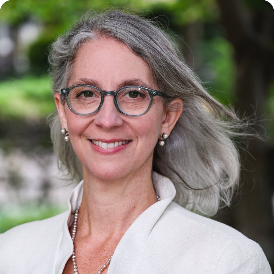 Rebecca Winthrop, smiling, with long gray hair and glasses, outdoors