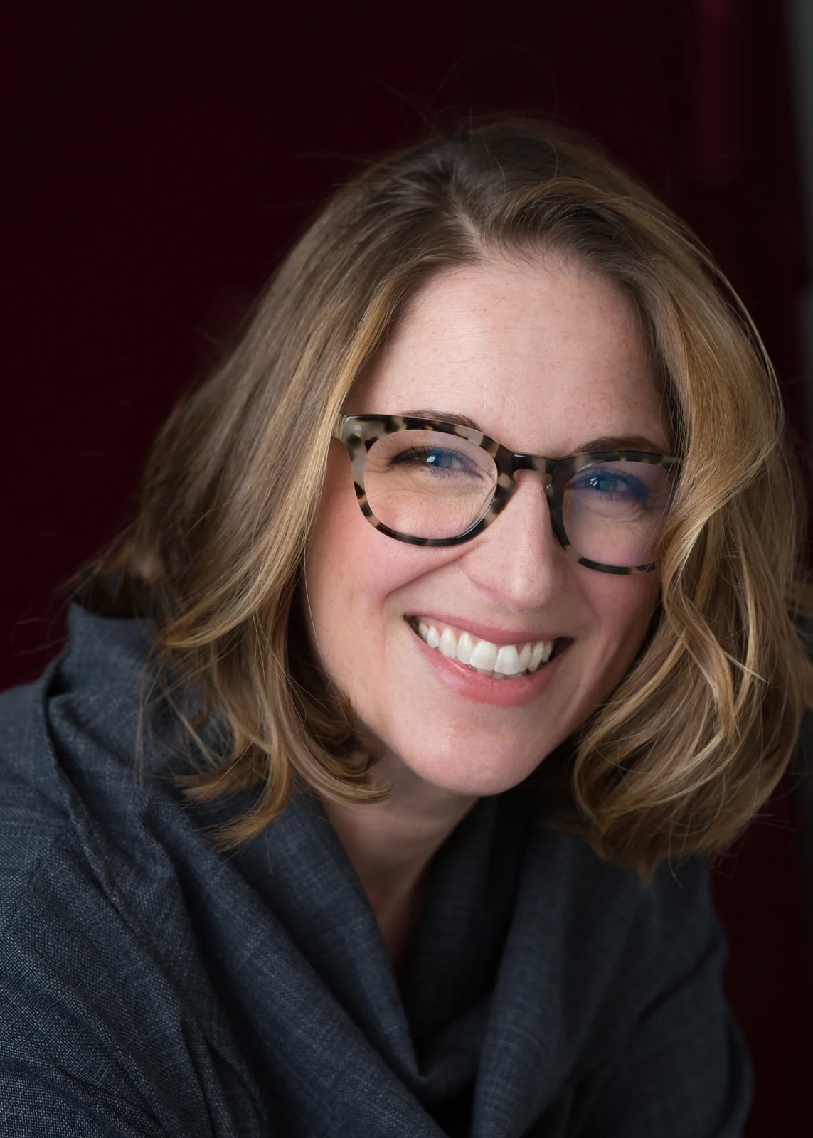 Jessica Lahey, smiling, in tortoiseshell glasses and a gray top