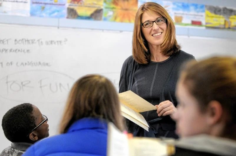 Jessica Lahey smiling in front of a whiteboard as she teaches, students in the foreground